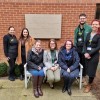 Staff and patients together in a garden at York Hospital. Some are sat on a bench, others are stood around the bench.