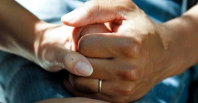 Close-up of two people holding hands, showing a gentle, supportive gesture.