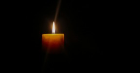A single lit candle glowing in darkness.