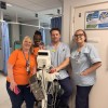 Hospital staff standing beside clinical monitoring equipment in a hospital ward.