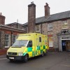An ambulance parked outside an entrance to an old hospital building.