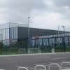 The outside of the new York Community Stadium with car parking and football pitch in front of the building