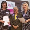 Geraldine and Stefanie posing onstage alongside Professor Dame Elizabeth Anionwu.