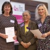 Geraldine and Stefanie posing onstage alongside Professor Dame Elizabeth Anionwu