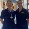 Caroline and Debbie, palliative nurses at the Trust, standing on a hospital corridor in their work uniforms.