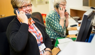 Two female receptionists on the phone at a desk smiling