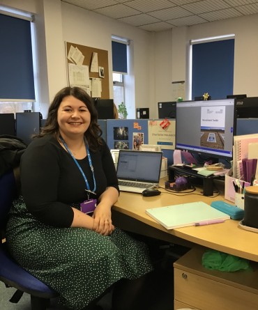 A woman is sat at a desk in an office.
