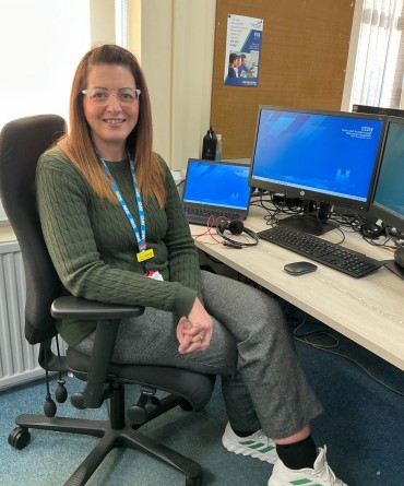 Jenn sitting on an office chair alongside her work desk.