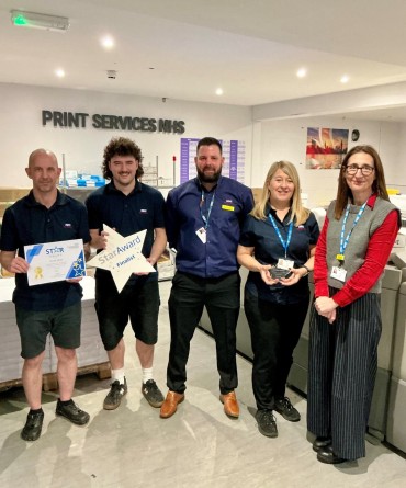 Star Award winners, Print Shop, receiving her award from Chief Executive, Clare Smith. They are wearing their uniform and stood within the print services building.