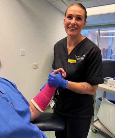 Jo applying a pink cast to a patient's arm.