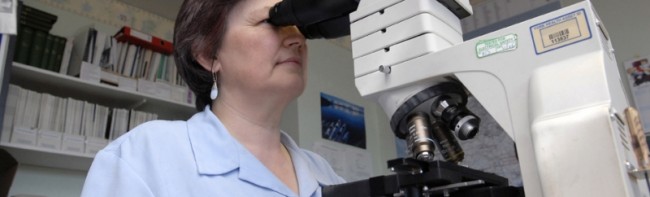 Woman looking into a large microscope