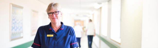 Member of staff standing in a hospital corridor.