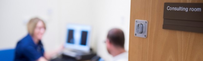 Banner image featuring a patient consultation taking place in a room with a 'consulting room' sign on the door.