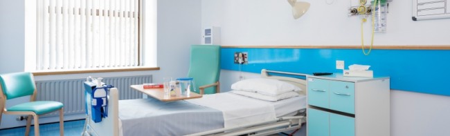 Banner image featuring an empty hospital room. There is a bed, two chairs, and a cupboard for a patient's personal belongings.
