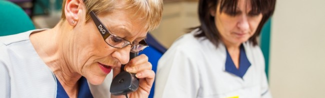 Two nursing colleagues sat at a desk, one woman on the phone