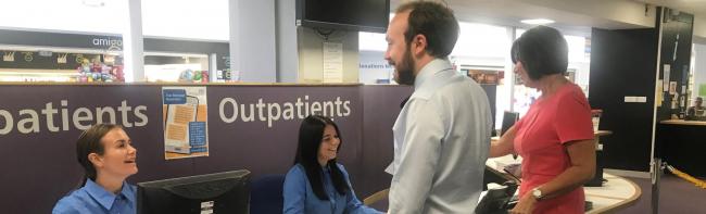 Outpatients reception desk with two receptionist serving patients who are checking into the hospital