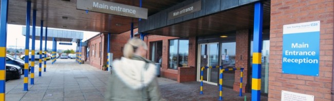 A person walking in front of a hospital building.