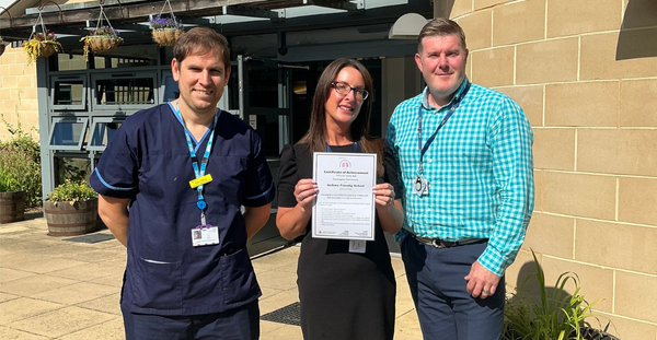 Alex, Kim, and Steve standing together. Kim is holding a certificate that recognises Danesgate's Asthma Friendly School accreditation.