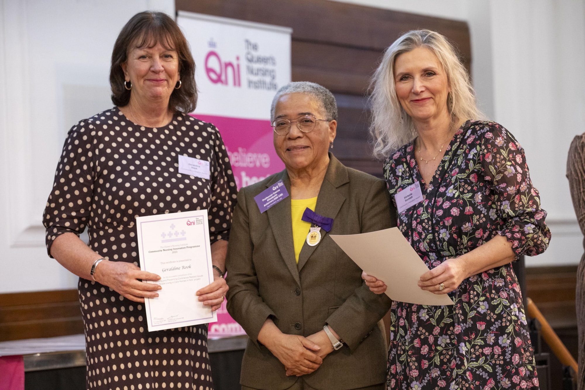 Geraldine and Stefanie posing onstage alongside Professor Dame Elizabeth Anionwu