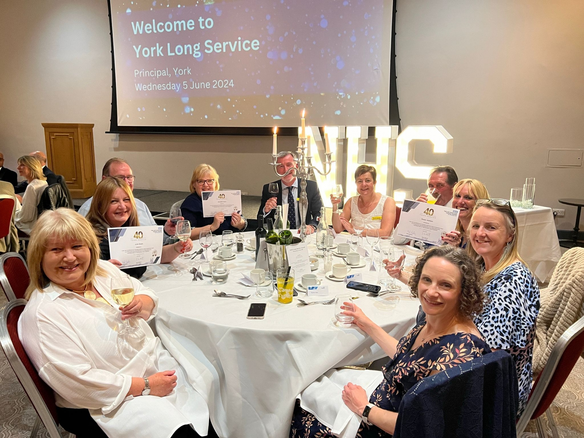 Staff sitting together around a table at a Long Service event.