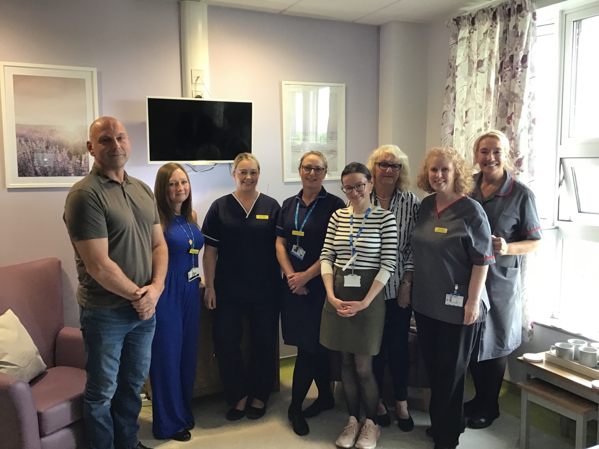 Staff and volunteers gathered together for a group photo in the palliative care room.